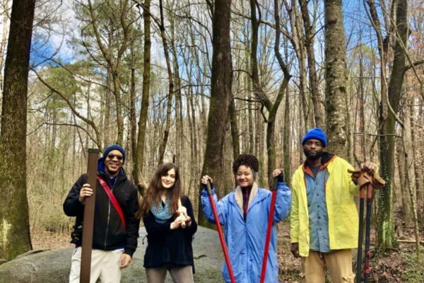 Four volunteers holding shovels in woods