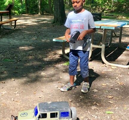 A man holding a remote control next to a toy truck.