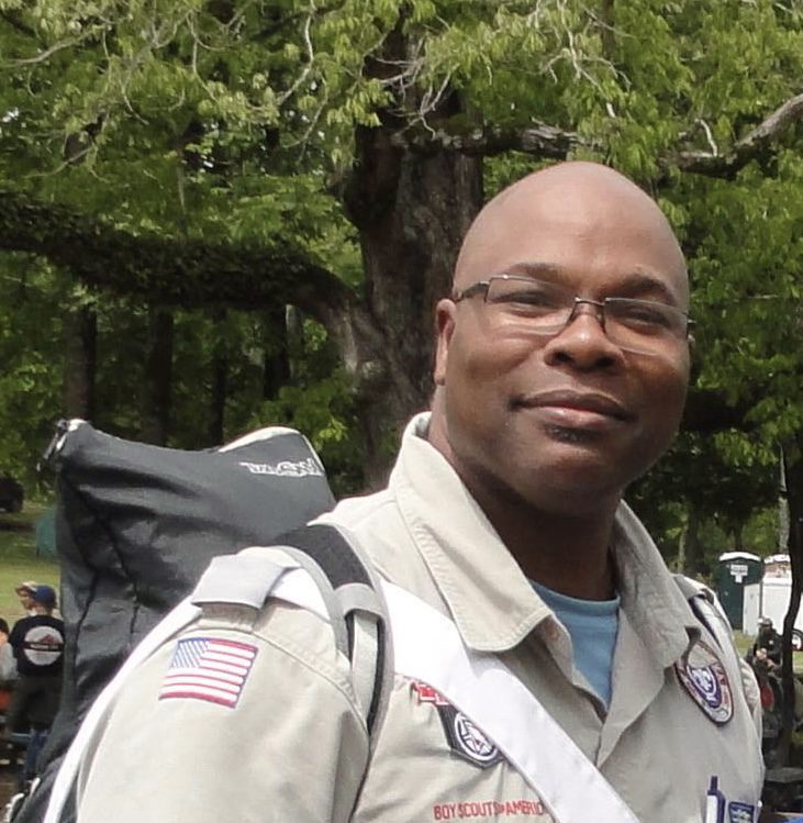 A man in uniform with a backpack and trees