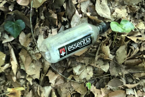 A bottle of water is laying in the leaves.