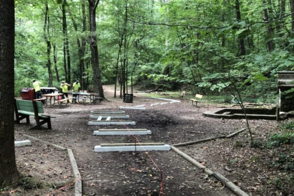 A trail in the woods with benches and picnic tables.