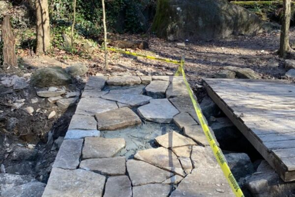 A stone walkway with a yellow measuring tape on it.