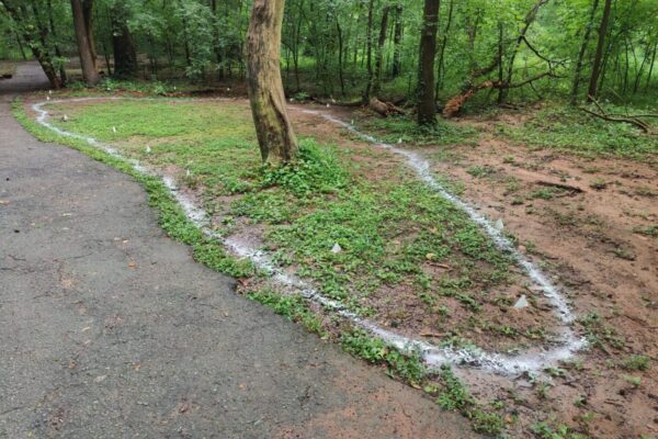 A trail of water is running down the side of a road.