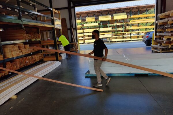 A man is moving some wood in a store.