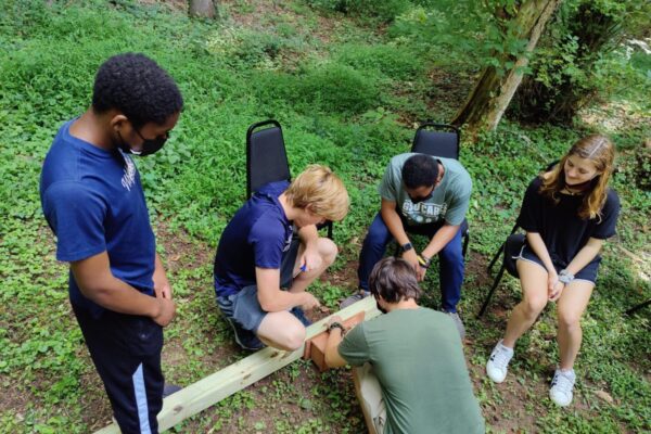 A group of people sitting around in the woods.