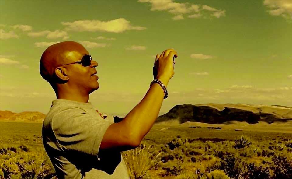 A man taking a picture of the sky with his cell phone.