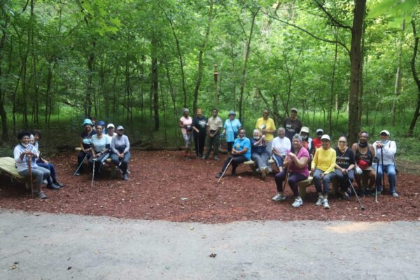 A group of people sitting on the ground in front of trees.