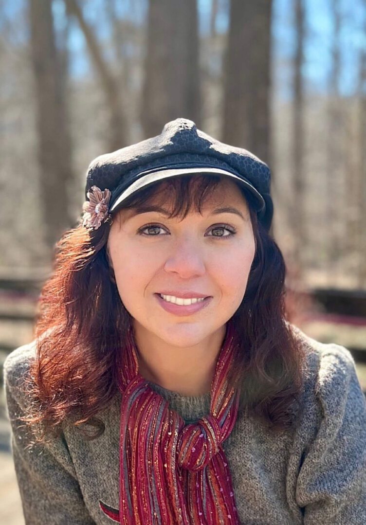 A woman with red hair wearing a hat and scarf.