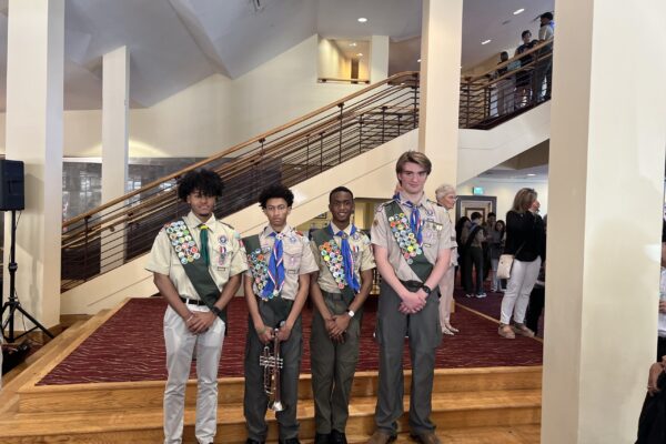 Four young men standing in front of a staircase.