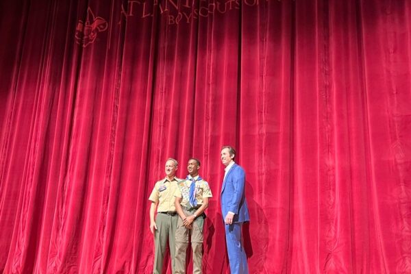 Three men standing in front of a red curtain.