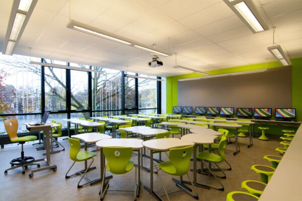 A classroom with green chairs and tables in it