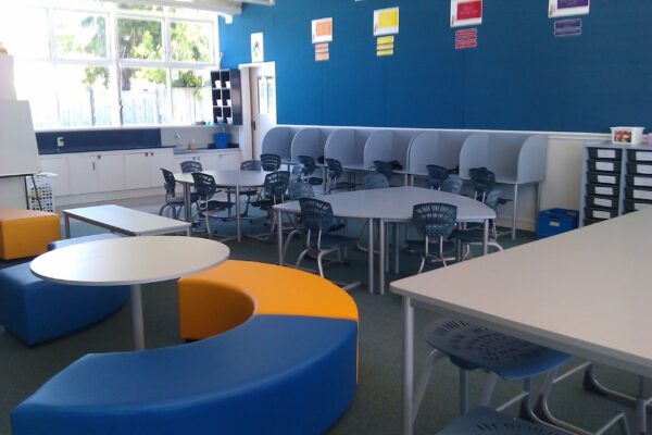 A classroom with tables and chairs, blue walls.