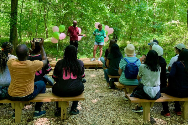 A group of people sitting on benches in the woods.