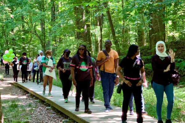 A group of people walking on a path in the woods.