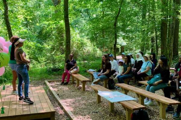 A group of people sitting on benches in the woods.