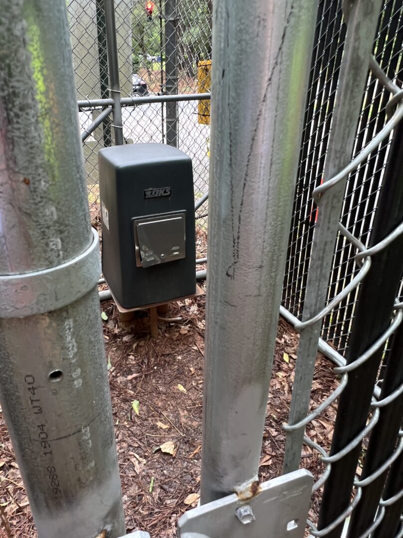 A metal fence with a black box on top of it.