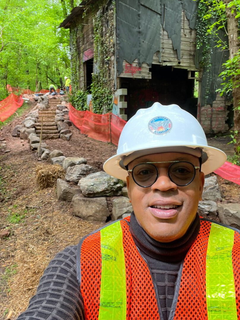 A man in safety gear standing on the side of a road.