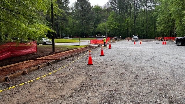 A road with orange cones and trees in the background.