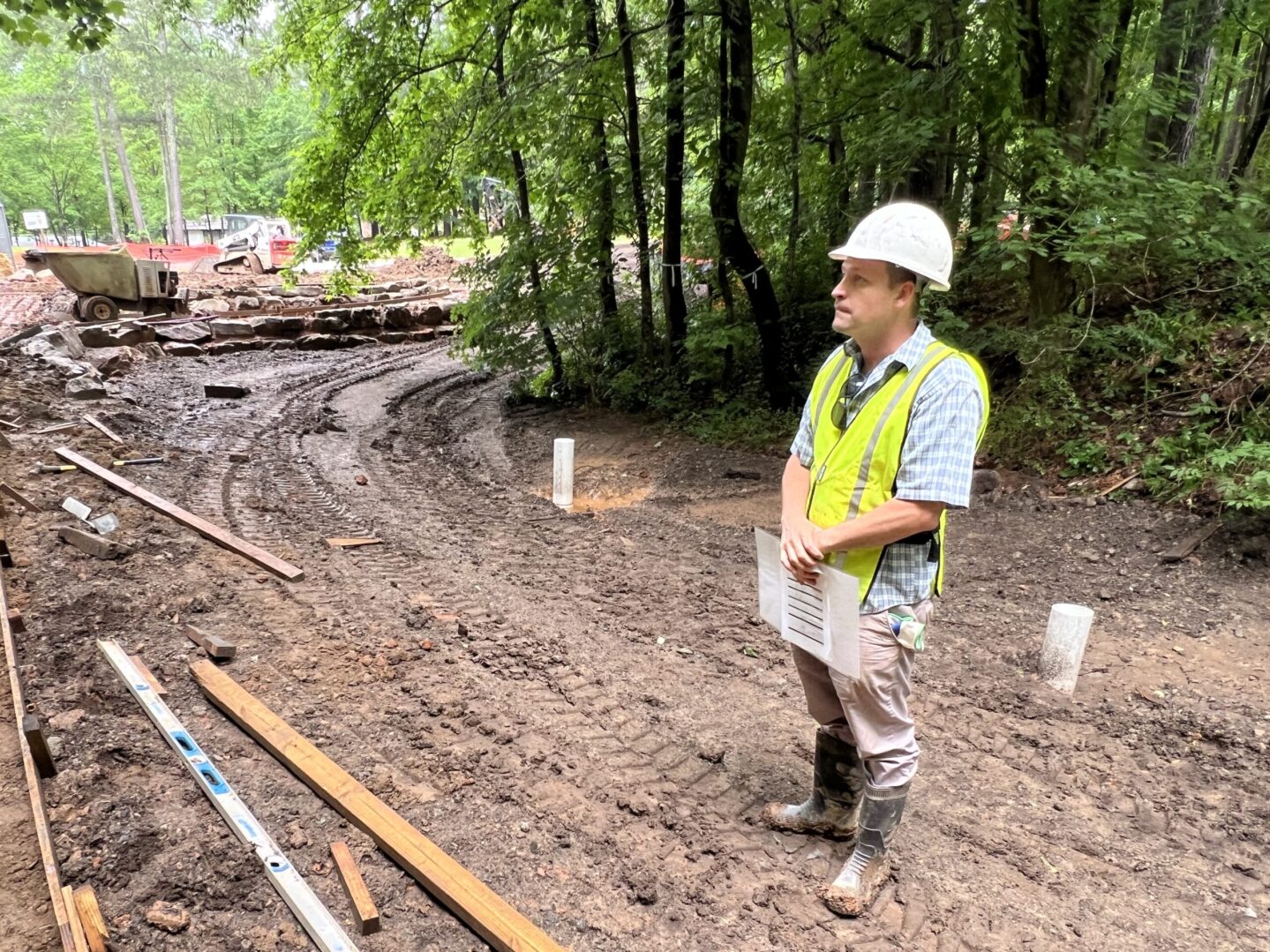 A man in safety gear standing on the side of a road.