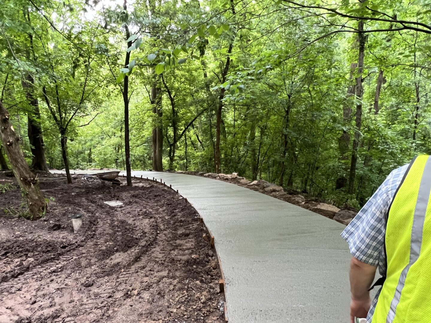 A man standing on the side of a path in the woods.