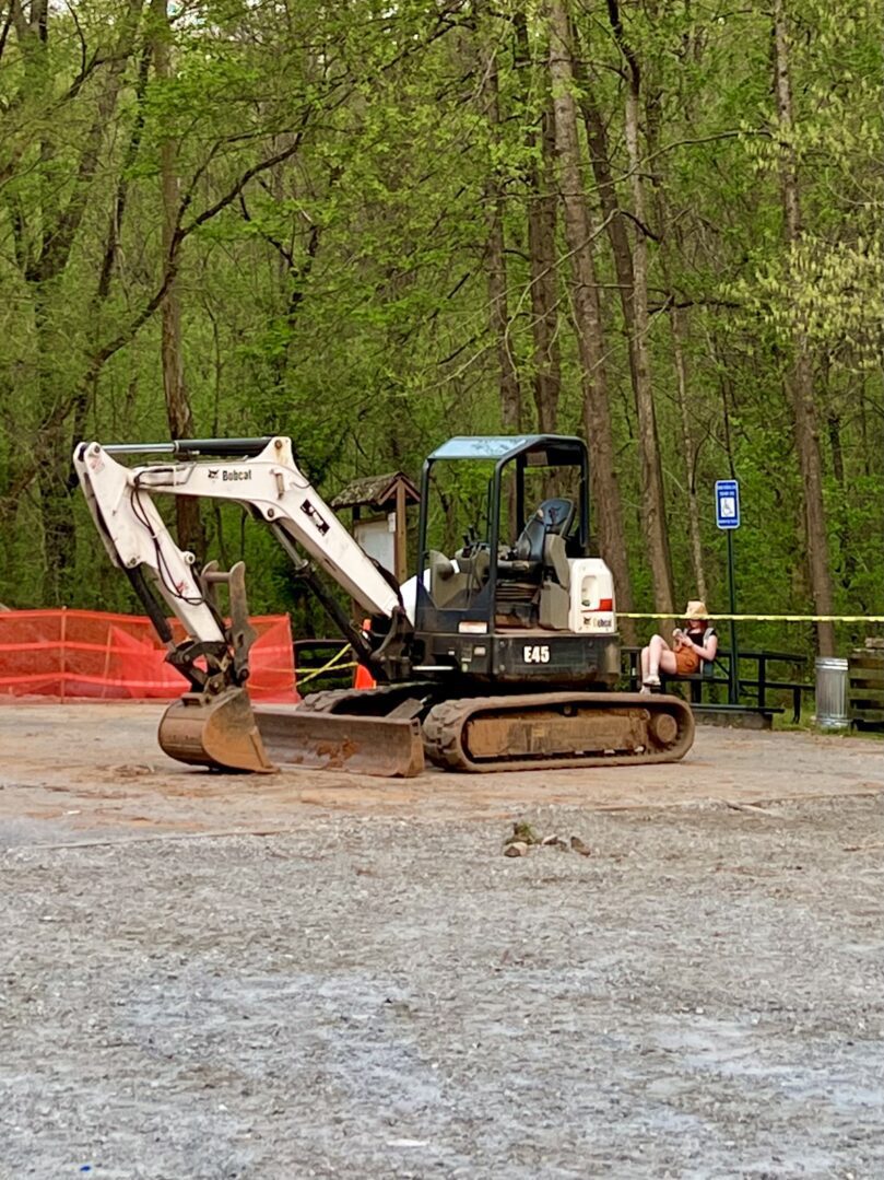 A white and black tractor is parked in the dirt.