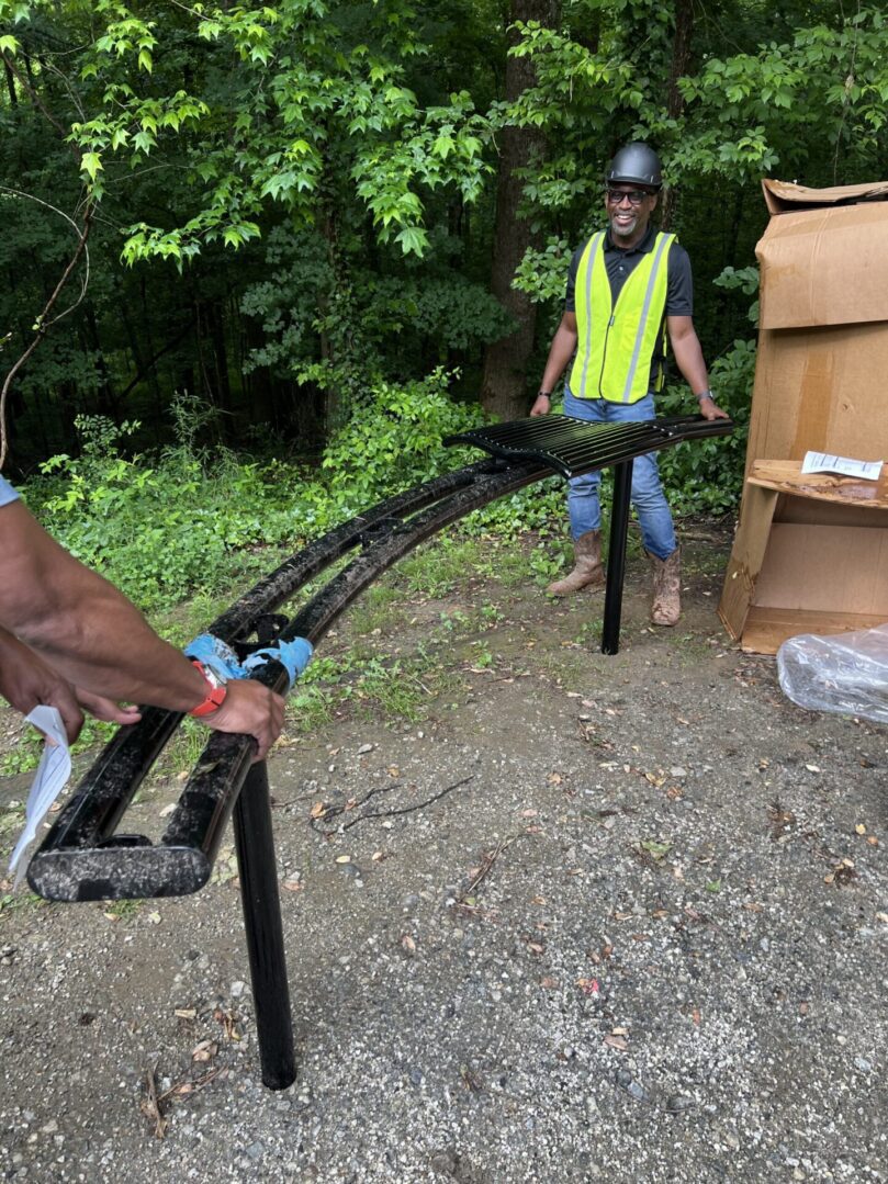 A man in reflective vest holding up a piece of metal.