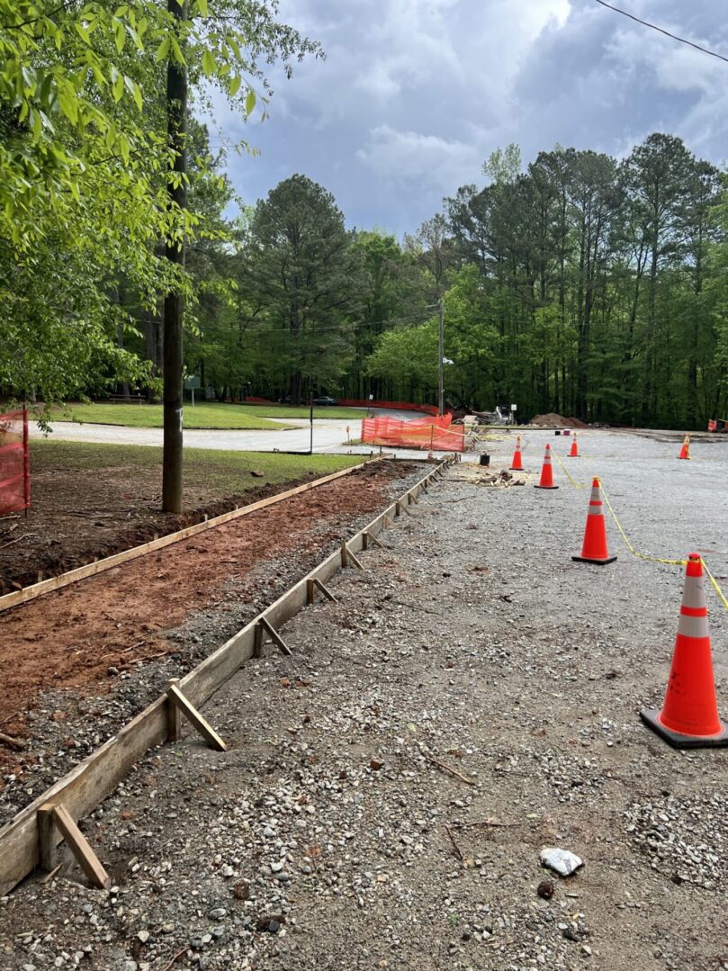 A road with orange cones and wooden poles.