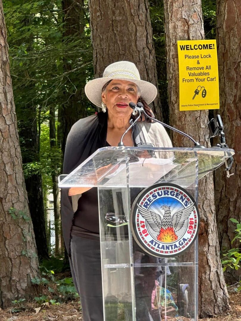 A woman in white hat standing at a podium.