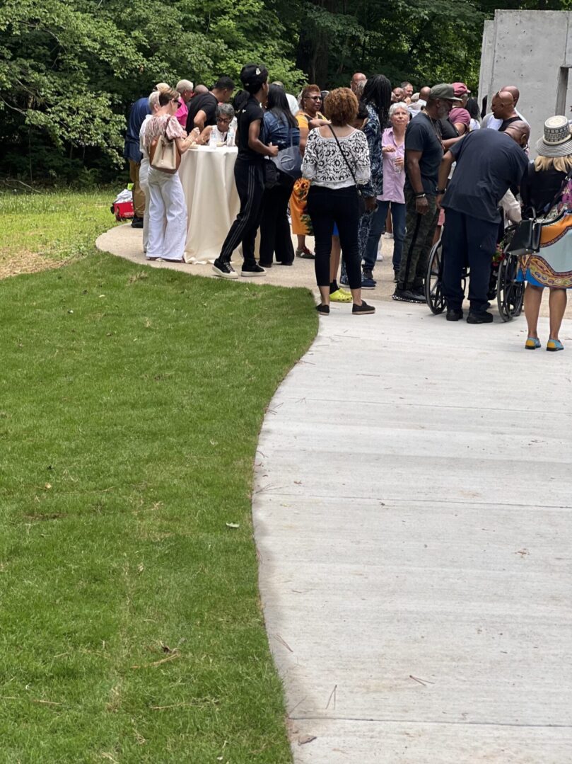 A group of people standing around on the sidewalk.