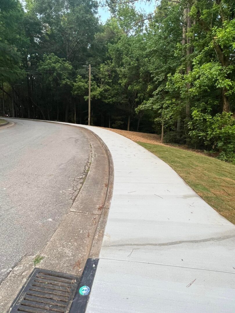 A sidewalk with trees and grass on the side.