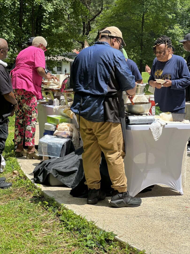 A group of people standing around tables with food.