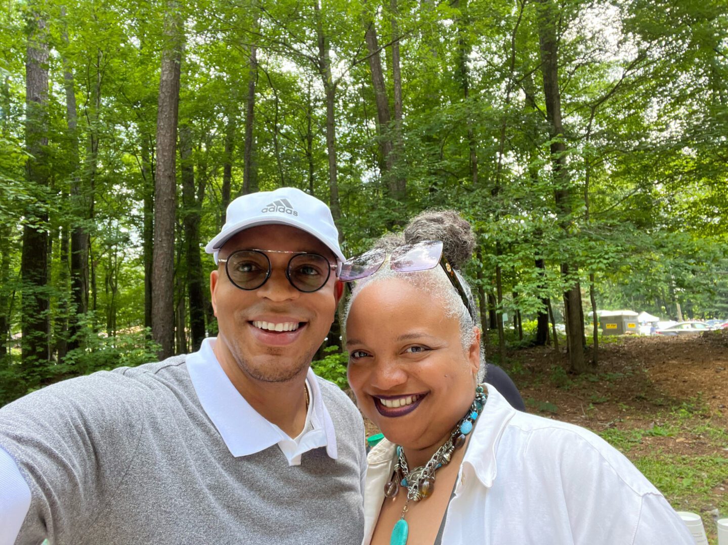 A man and woman posing for a picture in the woods.