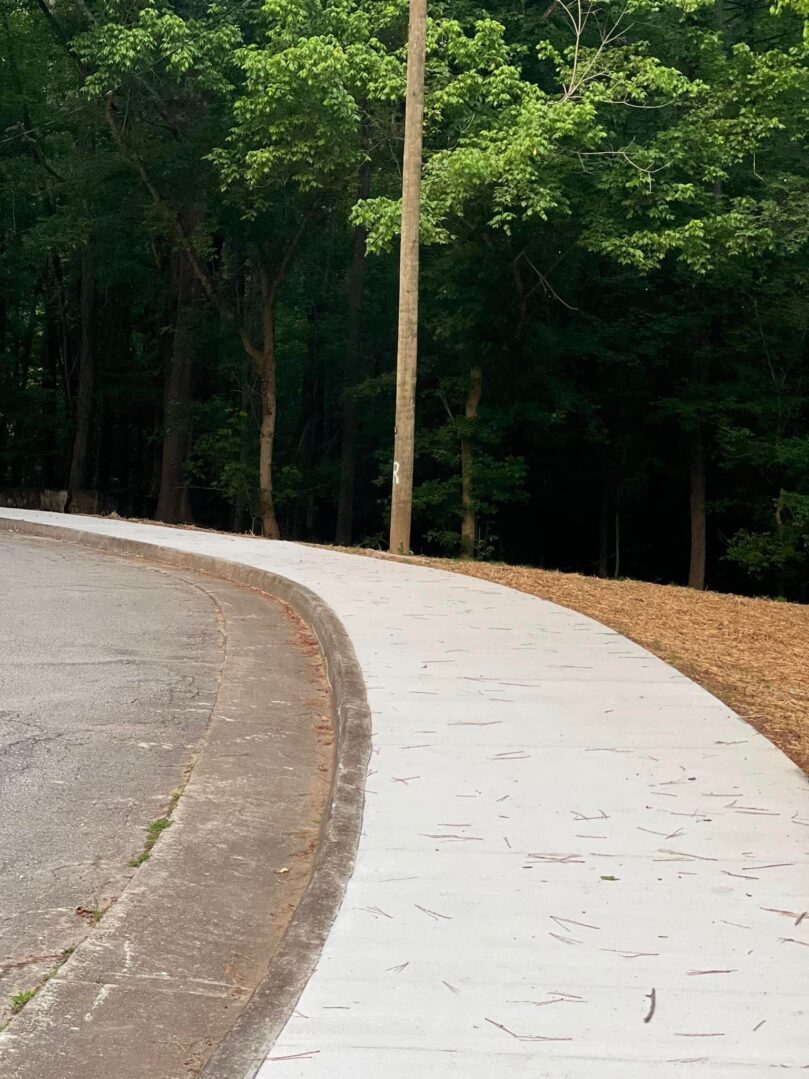 A sidewalk with trees in the background