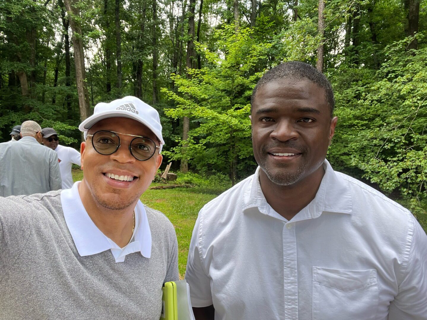 Two men standing next to each other in a park.