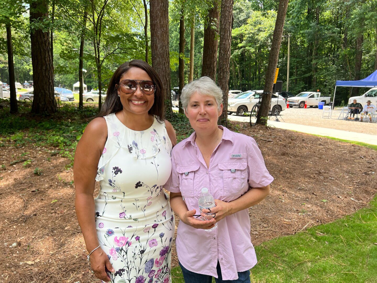 Two women standing next to each other in a park.