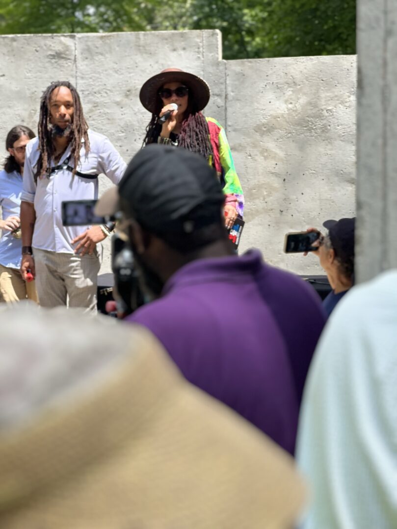 A man with dreadlocks and a hat is singing.