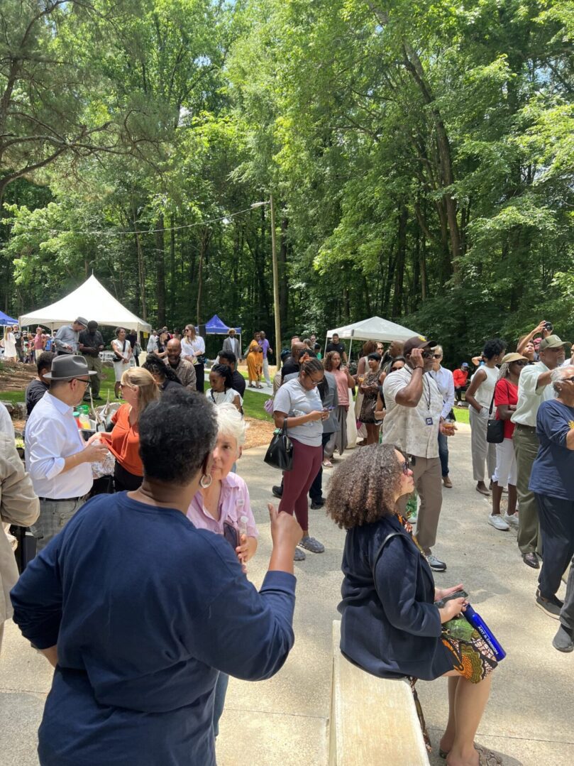 A crowd of people standing around in the woods.