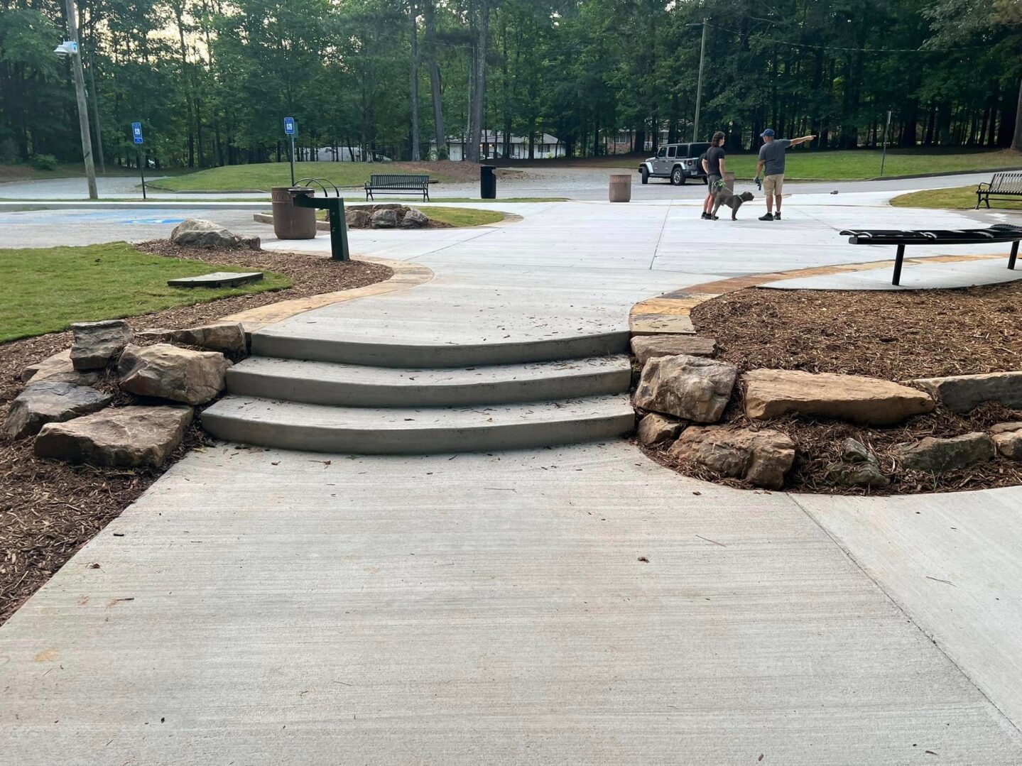 A concrete walkway with steps and rocks in the middle of it.