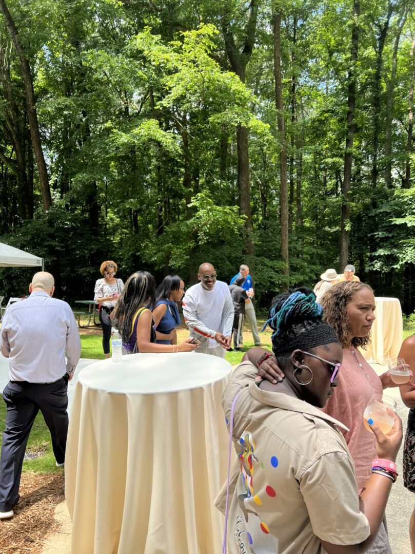 A group of people standing around tables outside.