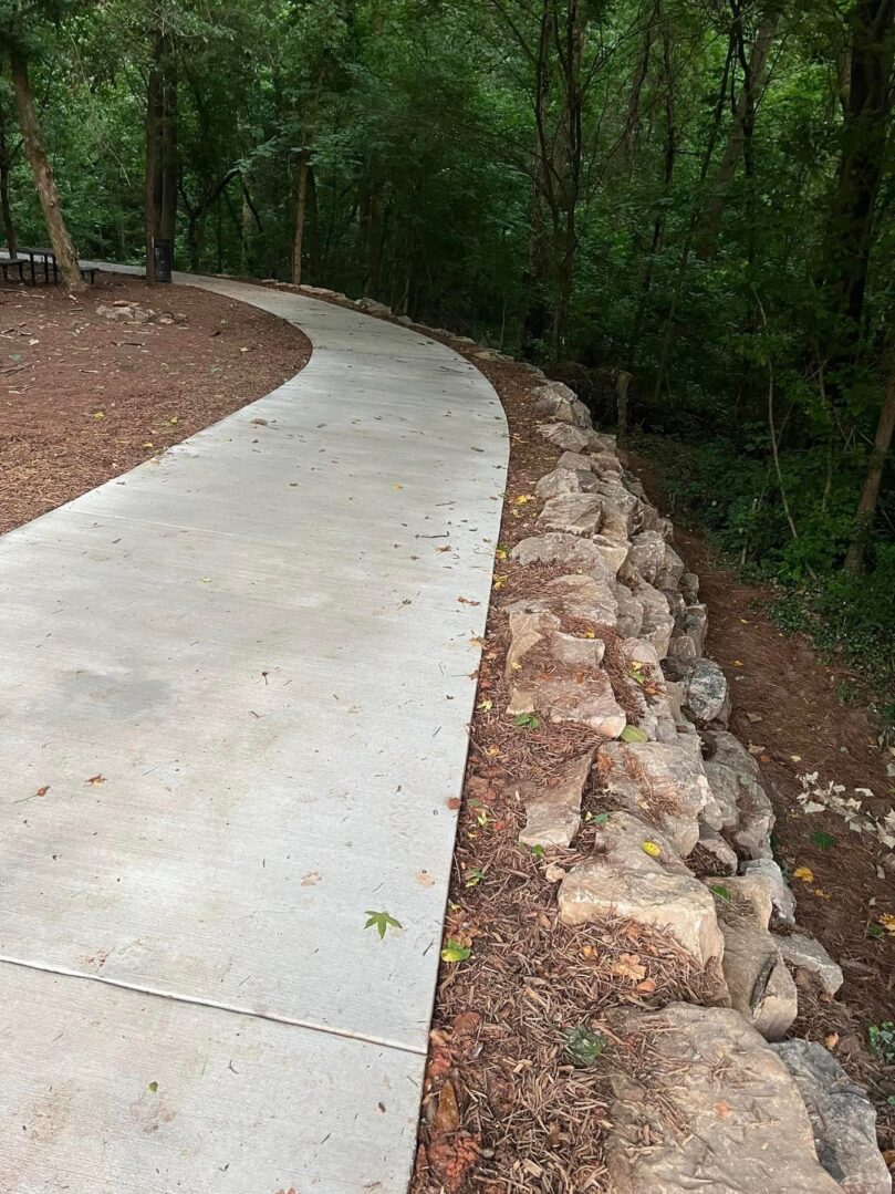 A concrete walkway with rocks on the side of it.