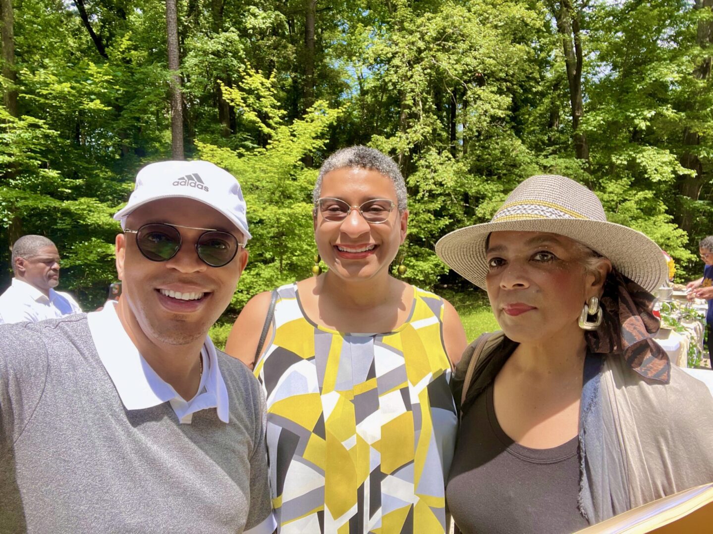 Three people standing in front of a forest.