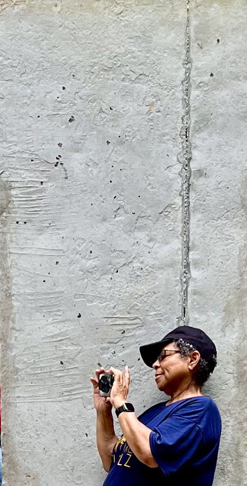 A man in a baseball cap standing next to a wall.