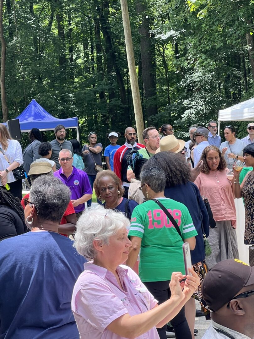 A crowd of people standing around in the woods.