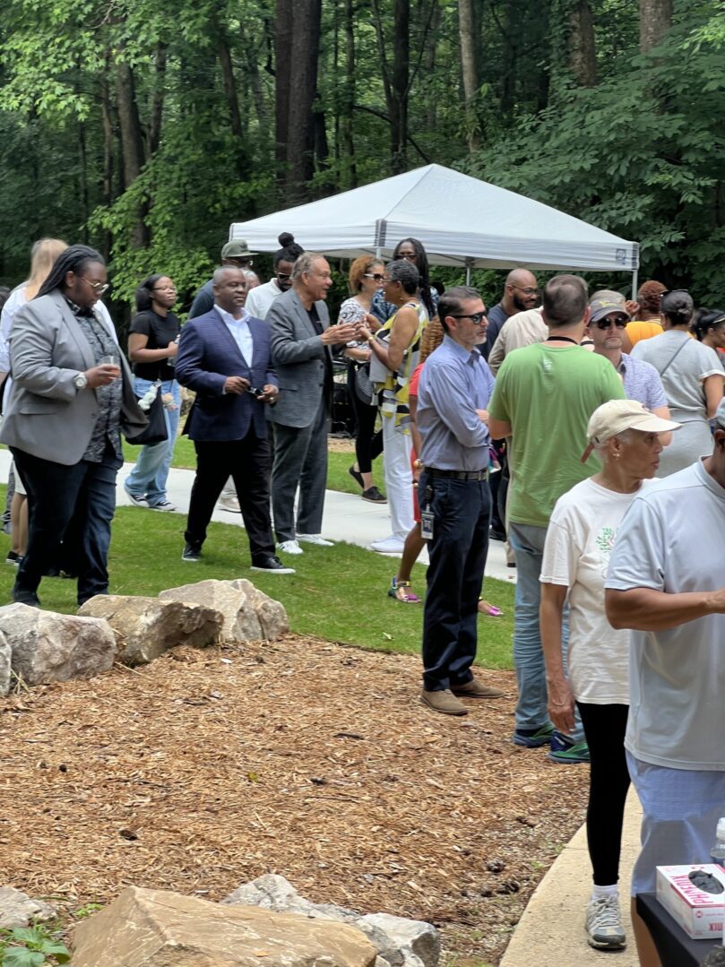 A group of people standing around in the grass.