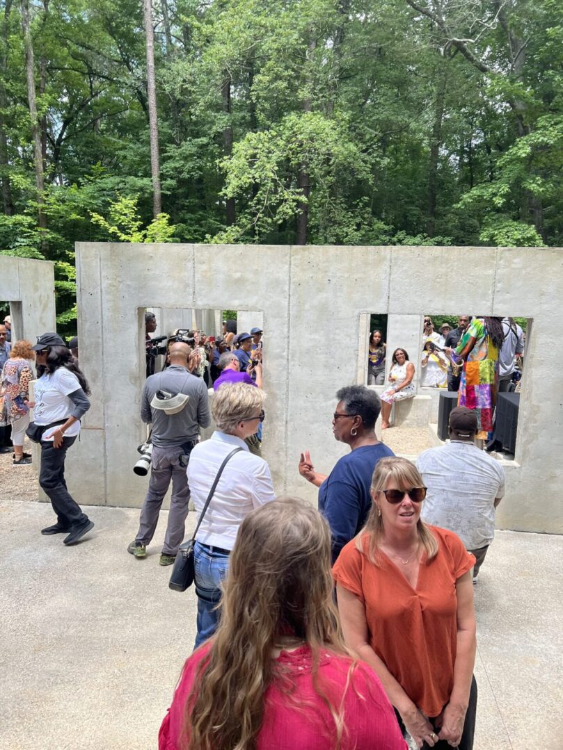 A group of people standing around in front of a wall.