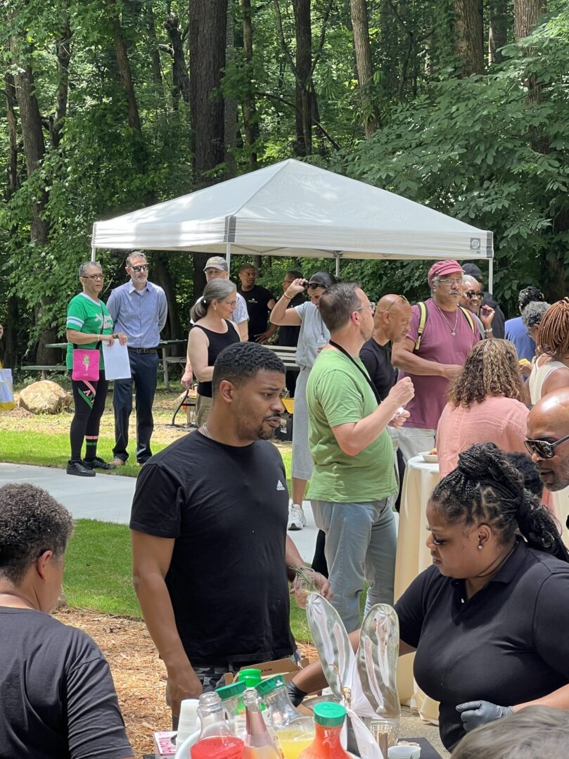 A group of people standing around in front of an outdoor tent.