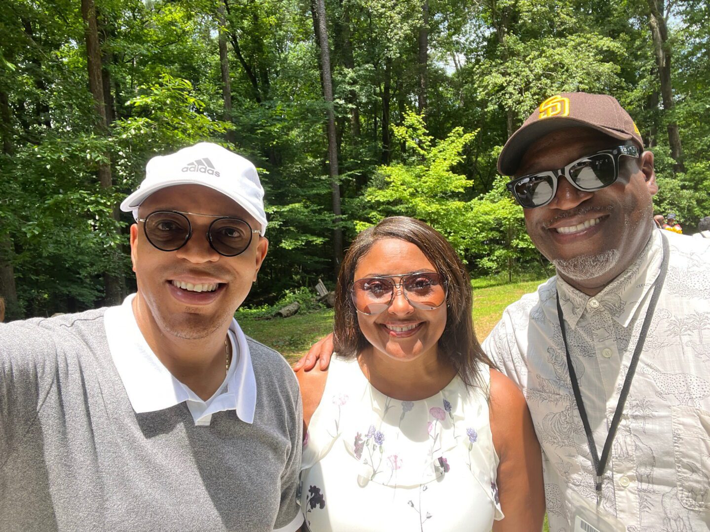 Three people posing for a picture in front of trees.