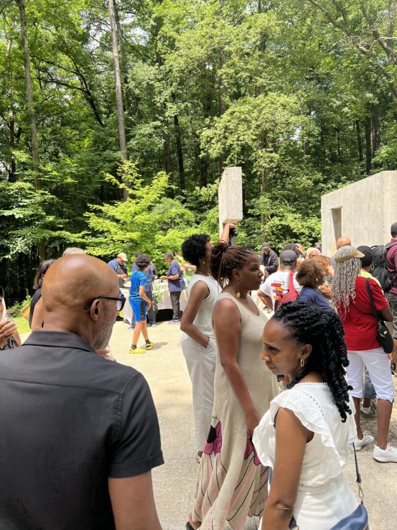 A group of people standing around in front of trees.