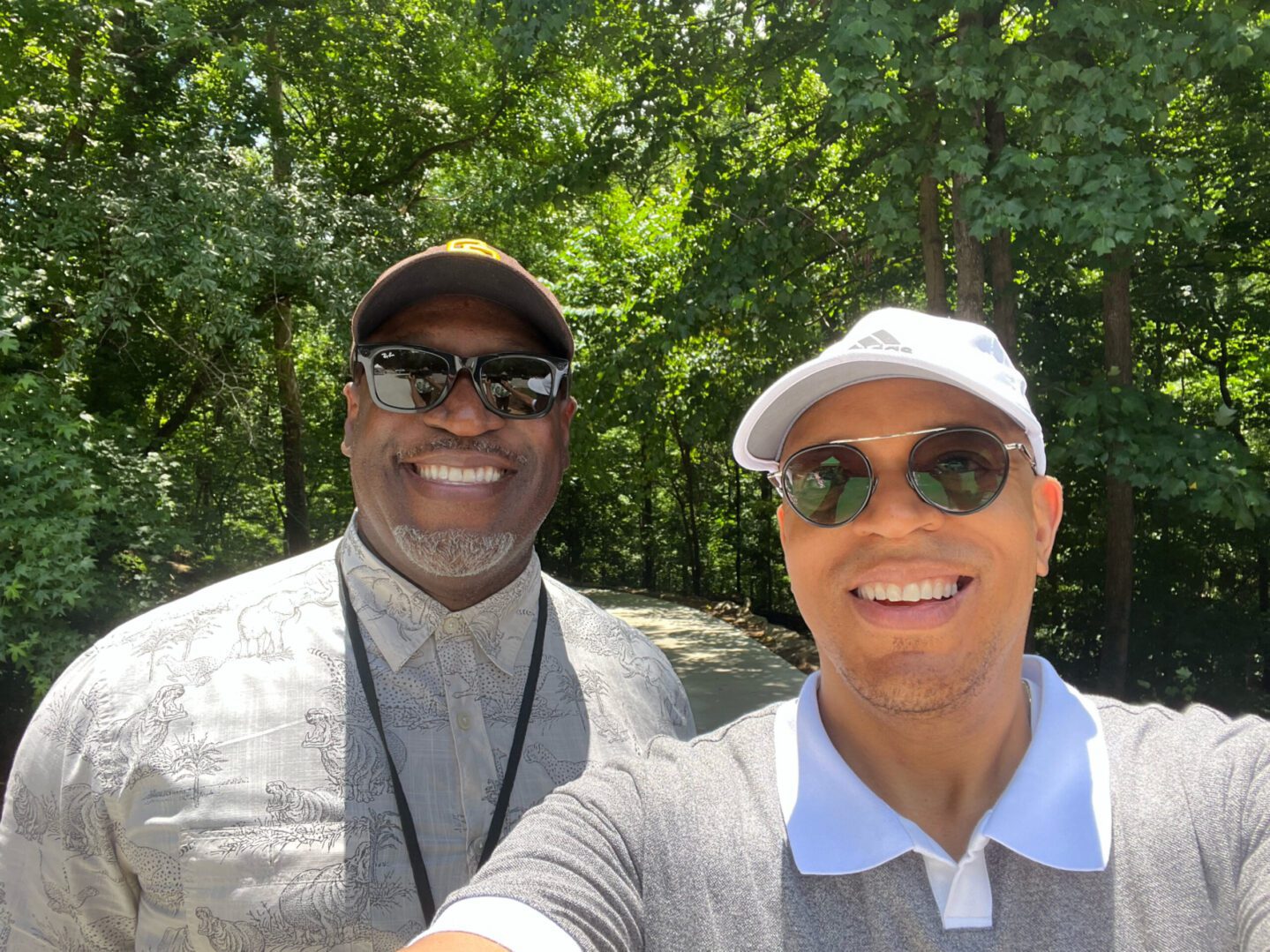 Two men taking a selfie in front of trees.