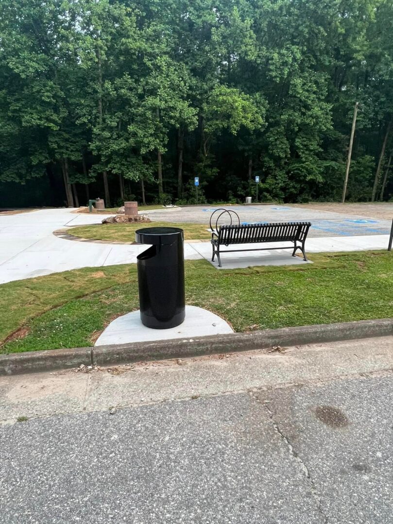 A bench and trash can in the middle of a park.